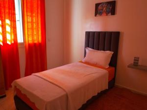 フェズにあるAppartement la perleの赤いカーテンが付いたベッドルームのベッド1台