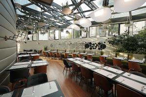 ein Esszimmer mit Tischen, Stühlen und Fenstern in der Unterkunft Hotel Berthelot in Bukarest