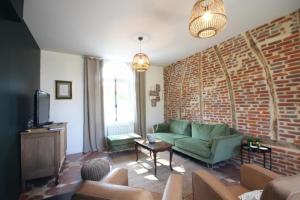 een woonkamer met een groene bank en een bakstenen muur bij Passage du Marché in Blainville-Crevon