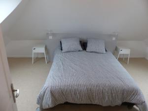 een slaapkamer met een bed met 2 kussens en 2 tafels bij Passage du Marché in Blainville-Crevon