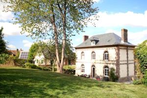 een oud stenen huis met een grasveld bij Passage du Marché in Blainville-Crevon
