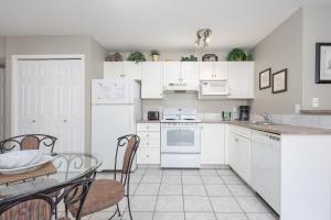 a kitchen with white appliances and a table and chairs at Paradise Canyon Golf Resort - Luxury Condo M403 in Lethbridge