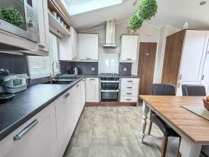 a kitchen with white cabinets and a wooden table at Beautiful Caravan With Decking At Azure Seas Ref 32060Az in Lowestoft