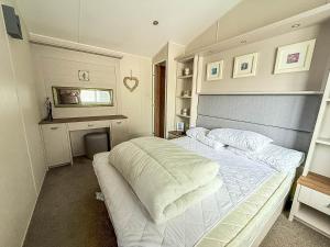 a bedroom with a bed with white sheets and a desk at Beautiful Caravan With Decking At Azure Seas Ref 32060Az in Lowestoft