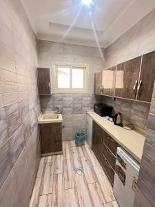 uma pequena cozinha com armários de madeira e um lavatório em Waha Residences-شقق الواحة em Al Madinah