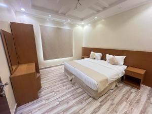 um quarto com uma cama grande e piso de madeira em Waha Residences-شقق الواحة em Al Madinah mais 4 fotografias