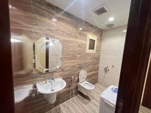 um banheiro com uma pia, um vaso sanitário e um espelho em Waha Residences-شقق الواحة em Al Madinah