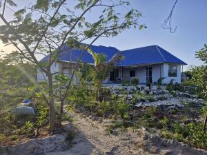 a white house with a blue roof at B&B G&H house Zanzibar in Pingwe