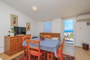 a dining room with a table and chairs and a television at Apartments Kata in Malinska
