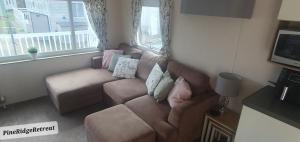 a living room with a brown couch with pillows at Pine Ridge Retreat With FREE GOLF and Air Conditioning in Morpeth