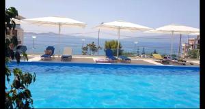a large swimming pool with chairs and umbrellas at Dania Sea View Apartments in Sarandë