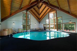 una piscina coperta in una casa con finestre di Domaine du lac long- Piscine & Spa- a Saint-Alphonse-Rodriguez