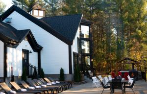 una casa bianca con sedie, tavoli e gazebo di Domaine du lac long- Piscine & Spa- a Saint-Alphonse-Rodriguez