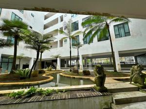 a building with a fountain in a courtyard with palm trees at Kuching Rex 2 bedrooms for 4 pax in Kuching