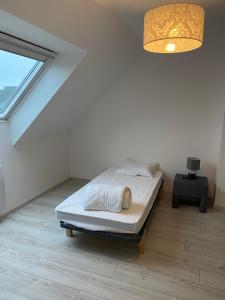 a white bedroom with a bed and a chandelier at Les sorbiers in Crozon