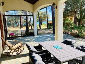 a patio with a wooden table and chairs on a porch at Villa de bord de plage in Pinarellu