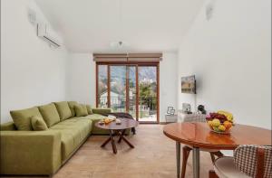 a living room with a green couch and a table at Apartmani Nadja in Škaljari