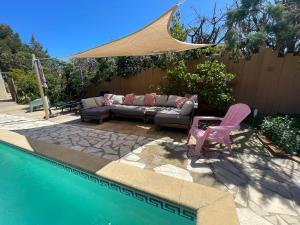 a patio with a couch and chairs next to a pool at Villa Casa azul in Cuxac-dʼAude