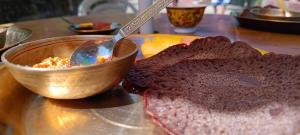 a bowl of food with a spoon and a piece of bread at Talay Ghar Homestay in Kaluk