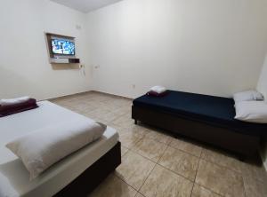 a bedroom with two beds and a tv in it at Apto Completo - Ar Condicionado e Garagem in Barretos