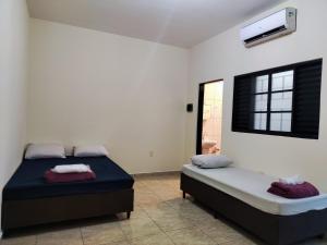 a bedroom with two beds and a window at Apto Completo - Ar Condicionado e Garagem in Barretos