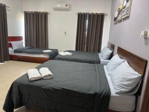 two beds in a hotel room with towels on them at Pangkor L30 88 Corner villa House in Pangkor