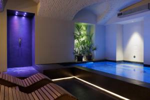 a swimming pool with a bench in a room at Palazzo Bellezia Luxury Suites & Spa in Turin