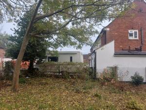 a white house and a brick building and a tree at A vroom with a view! in Eastcote