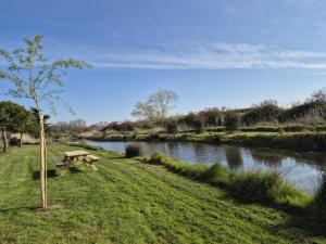 a park bench sitting next to a river at Villa de charme SPA - Piscine - Etang in Saint-Hilaire-de-Riez