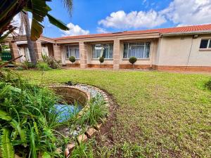 a house with a pond in front of a yard at Cozy Home with Pool, Braai & Top Security in Kempton Park