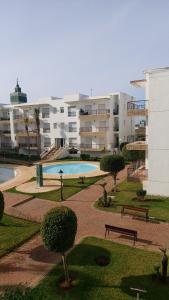 a park with two pools and benches and buildings at Bouznika DREAMS in Bouznika