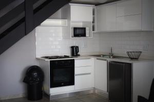 a kitchen with white cabinets and a black stove top oven at Forest-Riversend in Pietermaritzburg