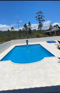 une grande piscine avec de l'eau bleue dans l'établissement Chácara Fazendinha Oliveira, à Mogi das Cruzes