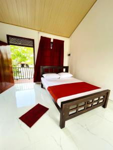 a bedroom with a large bed with a red curtain at Stay Lanka Guest House in Nikawatawana