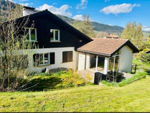 a small house with a black roof and a green yard at Appartement duplex spacieux in Fleurier
