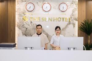 Dos personas de pie detrás de un mostrador con dos computadoras. en The Sun Hotel - Ninh Bình, en Kỳ Vĩ