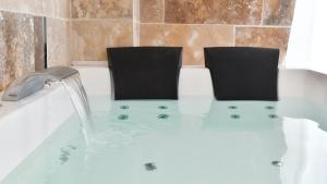 a bath tub filled with water with two chairs in it at Villa l'Insolente Spa Sauna Chambre 50 nuances de Grey in Lembras +66 photos