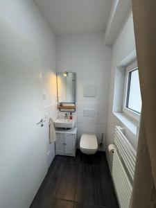 a white bathroom with a sink and a toilet at Tamm CityHub Zentral, Komfortabel, Tiefgarage in Tamm