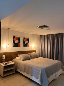 a bedroom with a large bed and a table at Apto 515 - Seu Refúgio na Praia - Nobile Hotel in João Pessoa