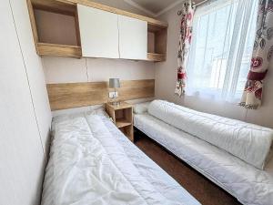 a bedroom with two beds and a window at Lovely 6 Berth Caravan At Caldecott Hall Country Park, Norfolk Ref 91010C in Great Yarmouth +15 photos
