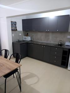 a kitchen with black cabinets and a table and a microwave at Blue House in San Nicolás de los Arroyos