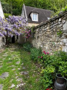 a stone wall with purple flowers and a building at LES TERRASSES (centre de Pierrefonds) in Pierrefonds