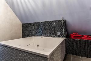 a white bath tub in a bathroom with red towels at Lustra Stundenhotel - Adults Only in Landshut
