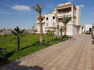 een wit gebouw met palmbomen ervoor bij القاهرة العبور الحي التاسع in Obour