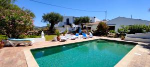 a swimming pool with chairs and a house at Casa da Timenina Privates Rooms in São Brás de Alportel