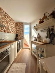 a kitchen with white cabinets and a stone wall at La Casita de las Vistas in A Guarda