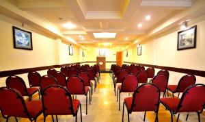 a conference room with red chairs and a podium at New Carnival Hotel in Kodaikānāl +26 photos