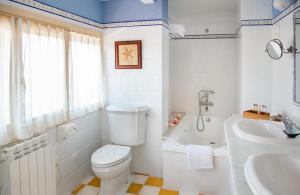 y baño con aseo, bañera y lavamanos. en Casona de La Paca, en Cudillero