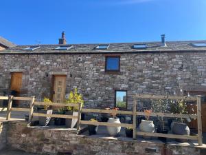 une maison en pierre avec des vases de fleurs devant dans l'établissement 200 yr old Barn Conversion ,Near Carlisle, the Borders and the North Pennines in peaceful village location, à Castle Carrock