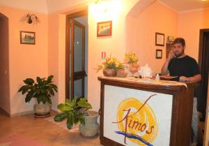 a man talking on a cell phone behind a podium with cats at Kimos in San Vito lo Capo